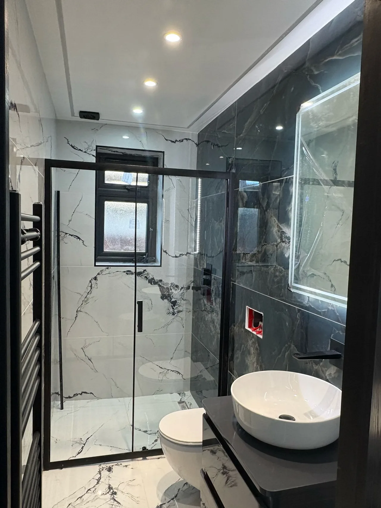 Black-framed shower screen with contrasting white and dark tiles