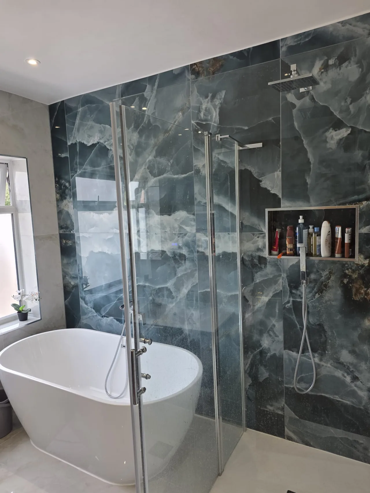 Freestanding bath, glass shower and dark stone-effect tiles