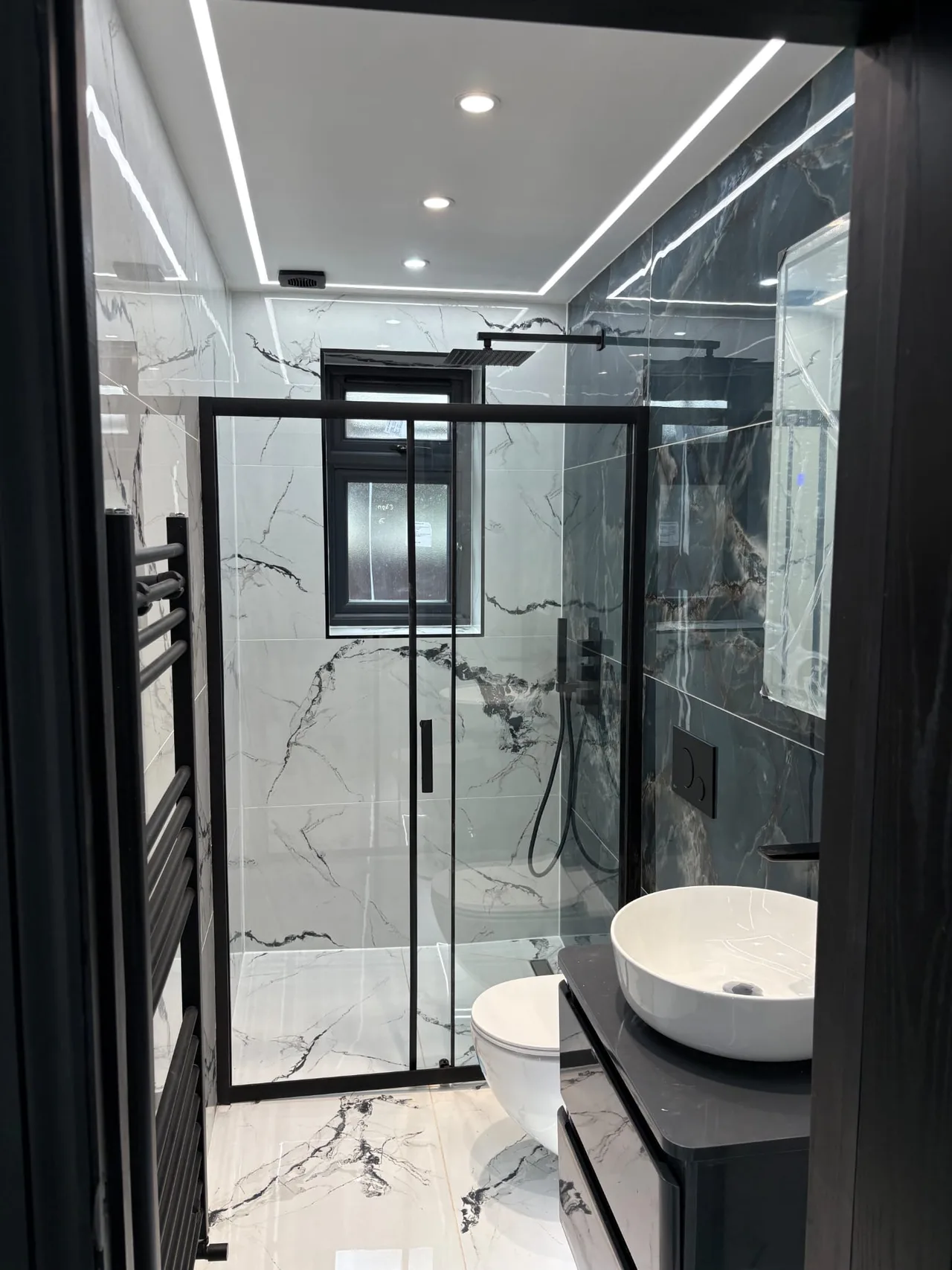Black-framed shower enclosure and white basin viewed from the doorway